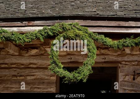 Une couronne de Noël artisanale à l'ancienne est suspendue dans une maison historique à la ferme Sauer Beckmann Living History Farm de Stonewall, au Texas. Banque D'Images