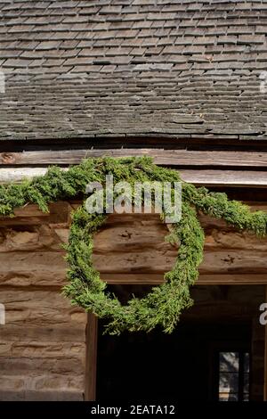 Une couronne de Noël artisanale à l'ancienne est suspendue dans une maison historique à la ferme Sauer Beckmann Living History Farm de Stonewall, au Texas. Banque D'Images