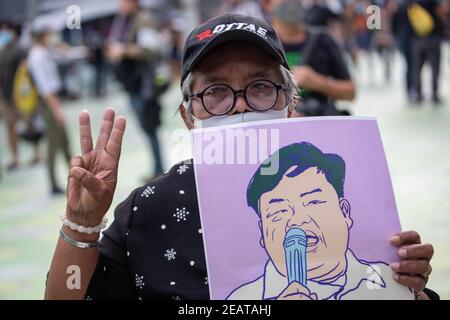 Une personne âgée salue les trois doigts tout en tenant le portrait de l'activiste Parit 'Penguin' Chiwarak lors d'une manifestation "make noise" pour dénoncer le récent coup d'État militaire de la junte au Myanmar et rejeter l'article 112 du code pénal thaïlandais.des milliers de manifestants pro-démocratie ont organisé une manifestation, A l'extérieur du centre commercial MBK de Siam, appelé « Make Noise » en faisant des coups d'ustensiles de cuisine en solidarité avec les manifestants anti coup d'État militaire au Myanmar et en rejetant la section 112 du code pénal thaïlandais. Les manifestants exigent également la démission du Premier ministre thaïlandais, Prayut Chan-o-cha and Banque D'Images