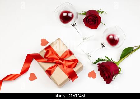 Roses rouges et verres à vin avec vin rouge sur fond blanc. Vacances et le jour de Valentin romantique appartement, concept de dessus de vue Banque D'Images