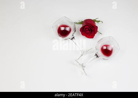 Roses rouges et verres à vin avec vin rouge sur fond blanc. Vacances et le jour de Valentin romantique appartement, concept de dessus de vue. Banque D'Images