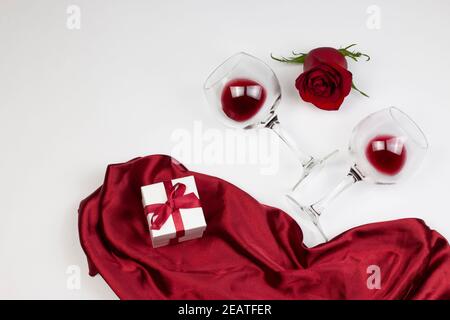 Vacances et le jour de Valentin romantique appartement, concept de dessus de vue. Roses rouges, verres à vin et boîte cadeau avec ruban rouge sur fond blanc Banque D'Images