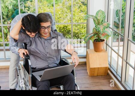 père homme assis en fauteuil roulant et son fils parlant des appels vidéo conférence sur ordinateur portable Banque D'Images