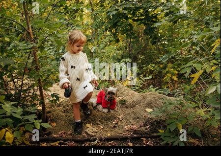 Enfant avec chien drôle marchant dans le jardin Banque D'Images