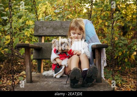 Un enfant avec un chien est assis dans une grande chaise en bois Banque D'Images