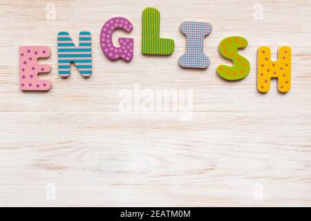 Mot anglais de lettres en bois colorées disposées sur fond blanc peint en bois vintage. Copier l'espace. Flat lay, vue de dessus Banque D'Images