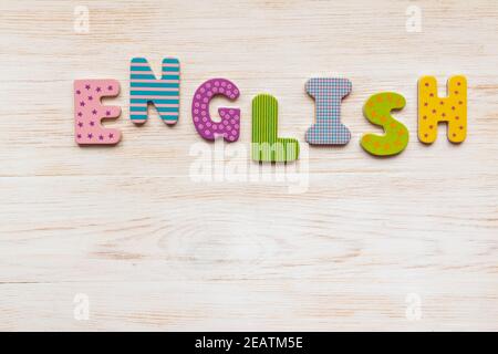 Mot anglais fait de lettres en bois colorées sur fond de bois peint blanc vintage. Flat lay, vue de dessus. Copier l'espace. Banque D'Images