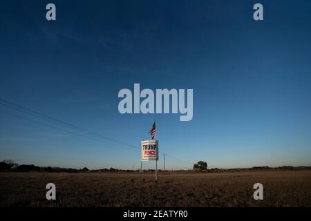 Smithville, Texas, États-Unis. 2 février 2021. Un agriculteur situé à l’extérieur de Smithville, dans le comté de Bastrop, au Texas, affiche un drapeau américain légèrement flatté par rapport à un panneau de campagne Trump-Pence trois mois après les élections de novembre, où le billet républicain a perdu. De nombreux Texans ruraux refusent encore d’accepter une victoire démocratique. Crédit : Bob Daemmrich/ZUMA Wire/Alay Live News Banque D'Images