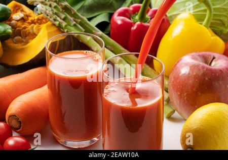 Beaucoup de différents types de légumes et de fruits sur un fond blanc et un verre de jus de légumes Banque D'Images