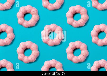 Beignets roses alignés régulièrement sur un fond bleu Banque D'Images