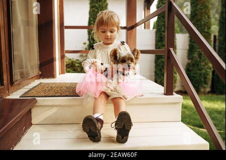 Enfant avec chien drôle sont assis sur les escaliers Banque D'Images