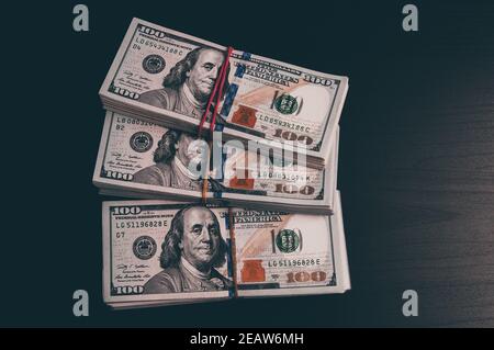Des wads de dollars en espèces sur une table sombre. Banque D'Images