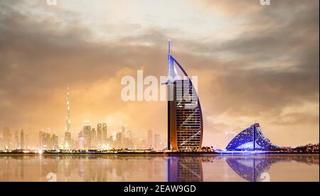 Coucher de soleil spectaculaire sur la ligne d'horizon de Dubaï avec le Burj Khalifa au loin et le Burj al-Arab hôtel de luxe en premier plan. Banque D'Images