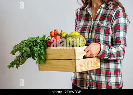 Femme tenant une boîte pleine de fruits et légumes sur blanc arrière-plan Banque D'Images