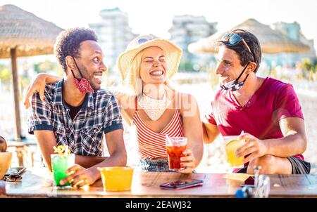 Groupe d'amis qui boivent des cocktails à la plage avec des masques ouverts - Nouveau concept normal de vacances avec les gens qui ont plaisir rire ensemble à chiringuito Banque D'Images