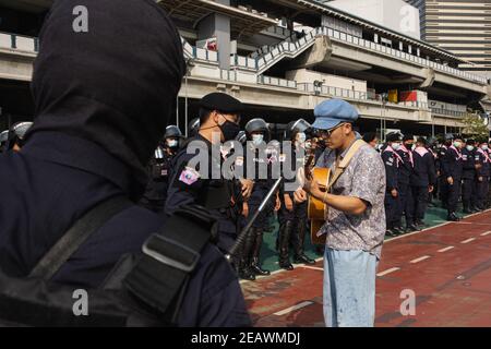 Bangkok, Thaïlande. 10 février 2020. Chaiamorn Kaewwiboonpan, activiste et chanteur joue une guitare à la police anti-émeute pendant la manifestation.les manifestants pro-démocratie ont établi l'événement "pot-banging contre la dictature" sur la passerelle en face du centre MBK et aussi sur la cour avant du centre artistique et culturel de Bangkok (BACC). Les manifestants ont exigé la démission du Premier ministre thaïlandais, Prayuth Chan-ocha, et des réformes de la monarchie. Après que des policiers aient arrêté 10 manifestants sous diverses accusations, telles que la loi sur le maintien de l'ordre public et de l'hygiène et le contrôle Banque D'Images