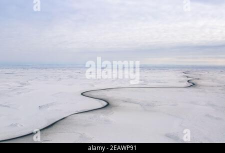 Vue aérienne en hiver de la route d'Inuvik-Tuktoyaktuk (construite au-dessus du pergélisol), en gravier toutes saisons de 139 km, dans l'Arctique canadien. Banque D'Images