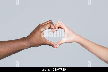 Les gens de différentes couleurs de peau mettent leurs mains ensemble faisant la forme de coeur dans le fond blanc. La charité, l'amour et la diversité - gros plan de femme et d'homme Banque D'Images