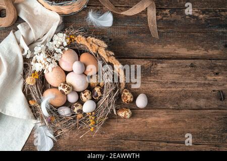 Joyeuses Pâques, fond festif avec des œufs dans un nid sur un fond en bois. Banque D'Images