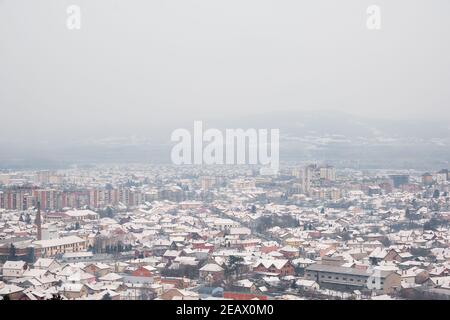 Vue en grand angle du paysage urbain enneigé de Pirot, Serbie, lors d'une journée d'hiver brumeuse, trouble et trouble Banque D'Images