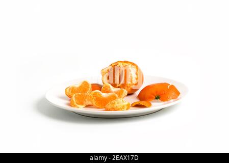 Epaillement de tangerines ou de clémentines dans une plaque blanche, isolée sur fond blanc Banque D'Images