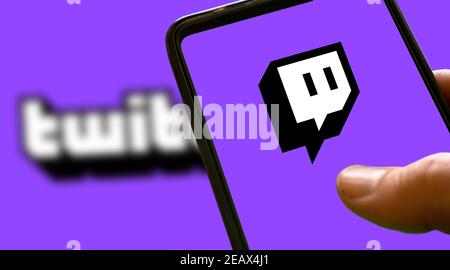 Logo twitch violet sur l'écran d'un smartphone avec fond violet et texte twitch flou. Icône de streaming de jeu Banque D'Images