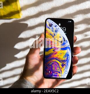 Paris, France - 25 septembre 2018: POV main mâle tenant de nouveaux Apple Computers iphone avec beau papier peint et fond rayé soleil Banque D'Images