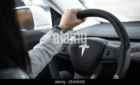 ingénieur tenant le volant tesla d'une main avec un montre apple sur son poignet Banque D'Images