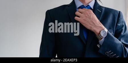 panorama d'un homme d'affaires qui ajuste son cravate bleue pour son costume monochromatique, et fond blanc avec beaucoup d'espace de copie Banque D'Images