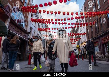 Les gens portant des masques de visage comme mesure préventive contre la propagation de la promenade Covid-19 le long de la rue de la ville de Chine à Londres.le nouvel an chinois est le plus grand festival en Asie. Chaque année, des centaines de milliers de personnes descendent généralement dans le West End de Londres pour assister à une parade colorée, à des spectacles sur scène gratuits et à la cuisine chinoise traditionnelle, et pour se souhaiter un autre « Xin Nian Kuai le » (bonne année en mandarin) ou « son Nin Faai Lok » (en cantonais). En raison des restrictions nationales de verrouillage, les gens peuvent profiter du divertissement du nouvel an chinois de Londres de la maison avec une célébration en ligne du passé Chine Banque D'Images