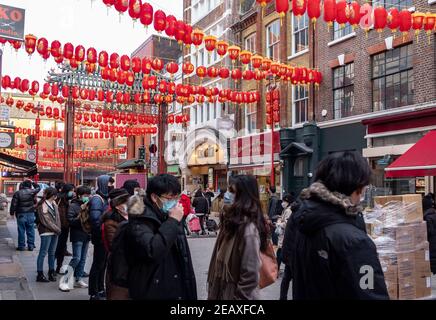 Les personnes portant des masques de visage comme mesure préventive contre la propagation de la file d'attente Covid-19 dans la boutique chinoise en façade à China Town, Londres.Chinese le nouvel an est le plus grand festival en Asie. Chaque année, des centaines de milliers de personnes descendent généralement dans le West End de Londres pour assister à une parade colorée, à des spectacles sur scène gratuits et à la cuisine chinoise traditionnelle, et pour se souhaiter un autre « Xin Nian Kuai le » (bonne année en mandarin) ou « son Nin Faai Lok » (en cantonais). En raison des restrictions nationales de verrouillage, les gens peuvent profiter du divertissement chinois du nouvel an de Londres de la maison avec une célébration en ligne de C passé Banque D'Images