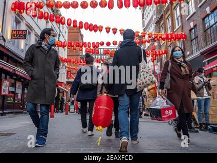 Les gens portant des masques de visage comme mesure préventive contre la propagation de la promenade Covid-19 le long de la rue de la ville de Chine à Londres.le nouvel an chinois est le plus grand festival en Asie. Chaque année, des centaines de milliers de personnes descendent généralement dans le West End de Londres pour assister à une parade colorée, à des spectacles sur scène gratuits et à la cuisine chinoise traditionnelle, et pour se souhaiter un autre « Xin Nian Kuai le » (bonne année en mandarin) ou « son Nin Faai Lok » (en cantonais). En raison des restrictions nationales de verrouillage, les gens peuvent profiter du divertissement du nouvel an chinois de Londres de la maison avec une célébration en ligne du passé Chine Banque D'Images