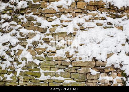 Jardin Cotswold mur en pierre recouvert de neige. Swinbrook, Cotswolds, Oxfordshire, Angleterre Banque D'Images