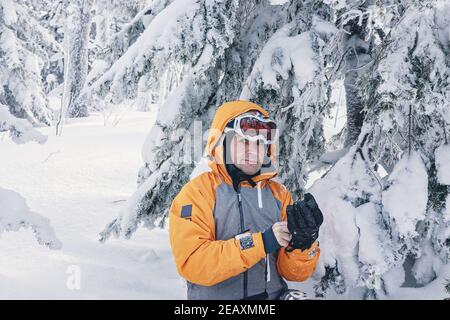 Portrait d'un snowboardeur mâle en costume brillant dans un casque de sport et des lunettes de ski sur fond de forêt enneigée. Sports extrêmes. Actif h Banque D'Images