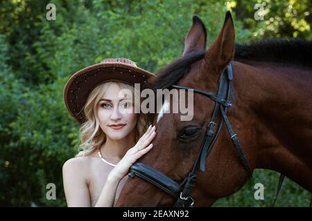 Belle jeune femme dans un chapeau de cow-boy près d'un cheval sur la nature dans le parc Banque D'Images