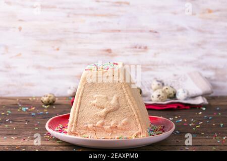 Dessert traditionnel russe au fromage cottage de Pâques, Paskha orthodoxe, avec du lait concentré bouilli et des noix arrosées de garniture de sucre sur une table en bois Banque D'Images