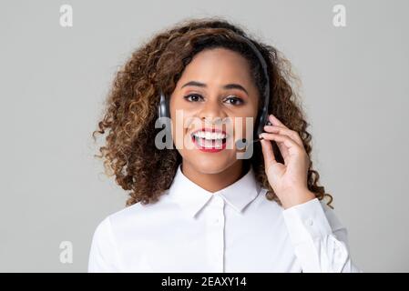 Service souriant femme afro-américaine sourit de porter des écouteurs le studio du personnel du centre d'appels a été tourné sur fond gris clair Banque D'Images