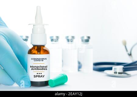 Le médecin tient un flacon d'anticorps monoclonaux en spray nasal, un nouveau traitement pour le coronavirus Covid-19, sur une table blanche avec quelques flacons et un stéthoscope Banque D'Images