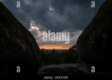 Placer avec beaucoup de grosses pierres couvertes de mousse dans un environnement orageux et jour de gris au coucher du soleil Banque D'Images