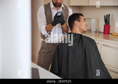 Visiteur charmant avec beau sourire obtenir des cheveux coupés à la maison appartements Banque D'Images