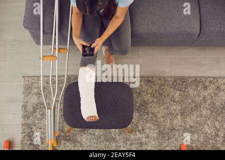 Femme photographiant sa jambe dans un plâtre moulé pour une consultation en ligne avec un médecin. Banque D'Images