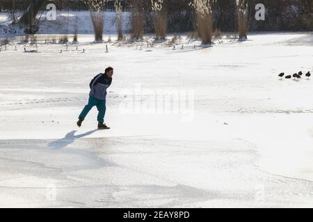 ZUTPHEN, PAYS-BAS - 10 févr. 2021: Patineuse de glace de loisir solitaire sur le lac naturel gelé l'après-midi ensoleillé froid Banque D'Images