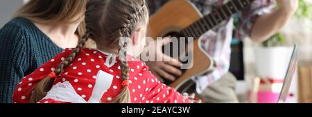 Fille, père et mère jouent des instruments de musique, guitare, pionino ensemble Banque D'Images