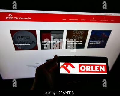 Personne tenant un téléphone portable avec le logo de la société polonaise de pétrole et de gaz PKN Orlen à l'écran en face du site Web d'affaires. Concentrez-vous sur l'affichage du téléphone portable. Banque D'Images