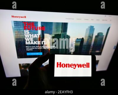 Personne tenant un smartphone avec le logo du conglomérat américain Honeywell International Inc. À l'écran devant le site Web. Mise au point sur l'affichage du téléphone. Banque D'Images