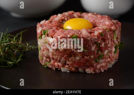 Tartare de boeuf avec œuf brut, et oignons, herbes fraîches. Cuisine française Banque D'Images