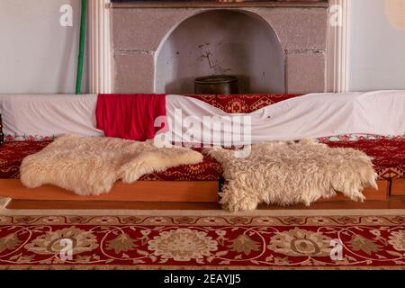 Cette chambre orientale est décorée de tapis et de peaux d''mouton. Le siège du grand-père alevi dans la maison cem. Banque D'Images