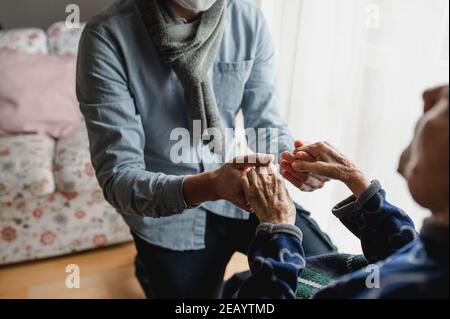 Jeune homme méconnaissable tenant les mains de la vieille femme. Personnes âgées, soins, concept de famille. Banque D'Images