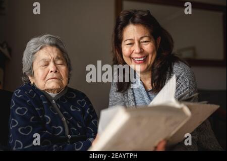 Vieille femme malade avec perte de mémoire. Fille souriante montrant un album photo. Banque D'Images