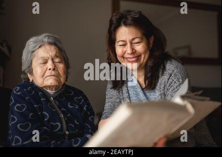 Vieille femme malade avec perte de mémoire. Fille souriante montrant un album photo. Banque D'Images